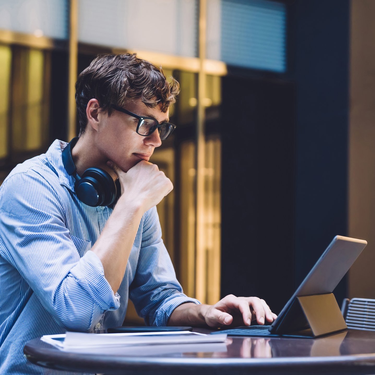 Person with headphones on at desk typing on laptop 